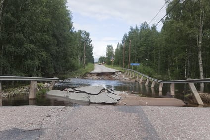 Broken asphalt near a bridge after heavy rain